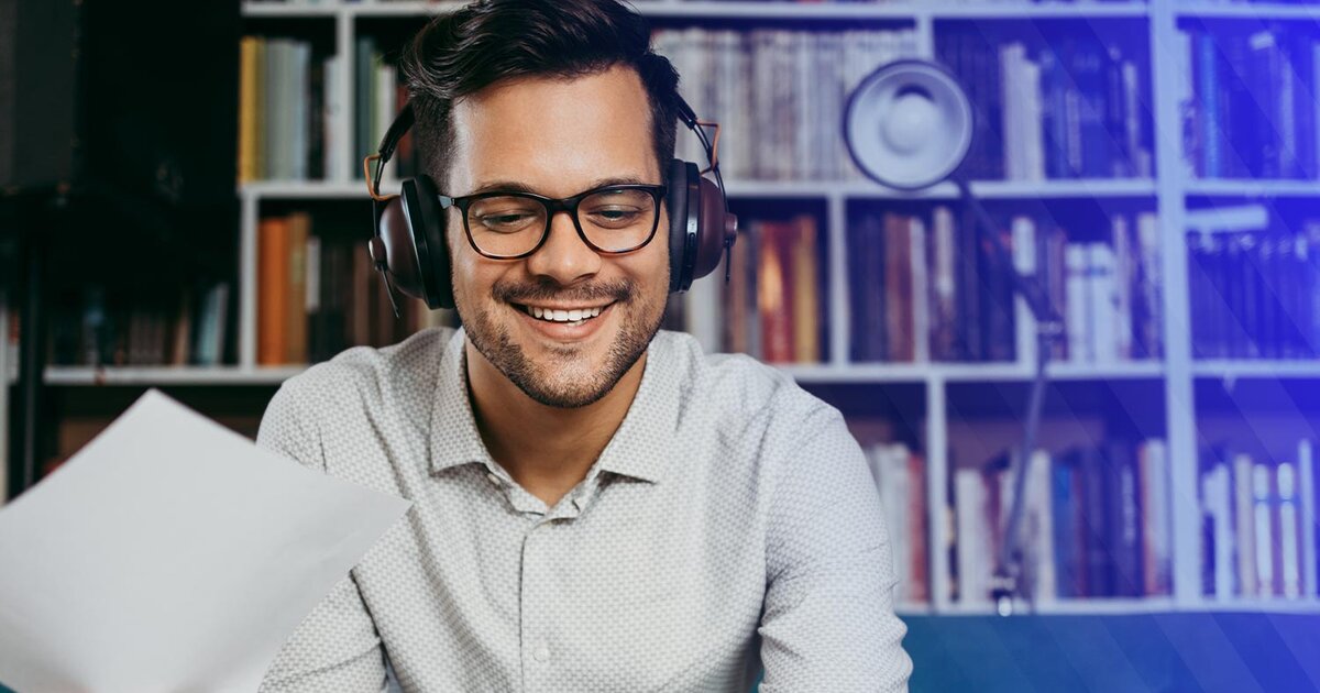 Smiling man with headphones looking at laptop