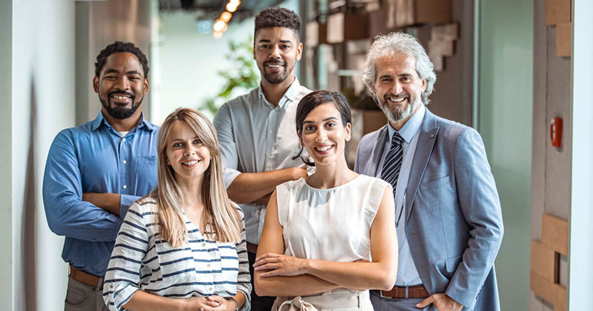 Coworkers pose and smile for a group photo in an office setting