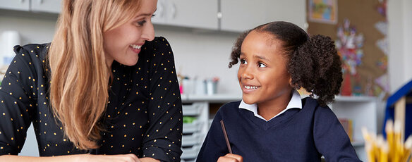 A teacher and middle school student work together at a classroom table.