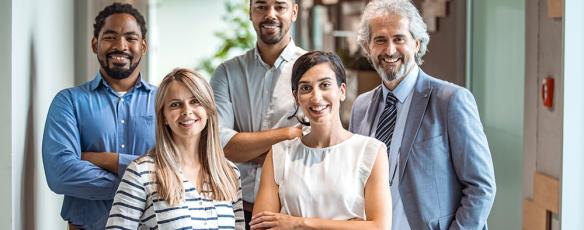 Coworkers pose and smile for a group photo in an office setting