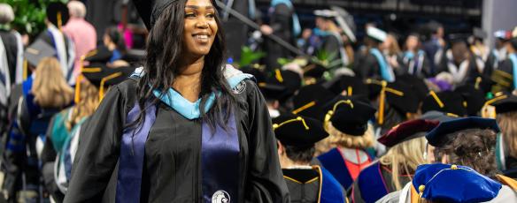 2024 Commencement image of a woman walking to the stage to receive her diploma with a smile