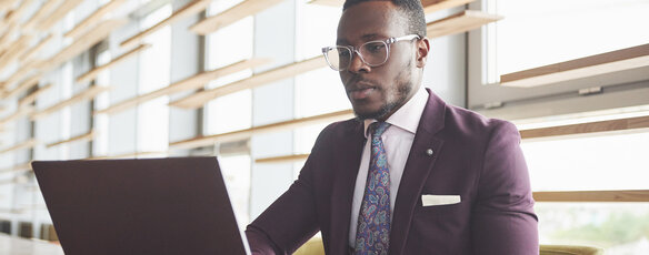 Man wearing a suit seated at a computer