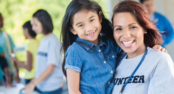 Female healthcare worker holding a young child after earning her Public Health Degree Online