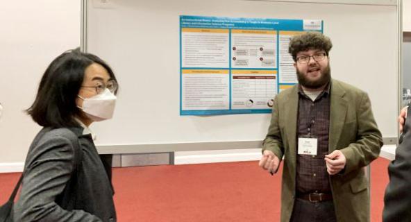 MLIS student Evan Dorman (right) talks about his research with visitors at a poster session.