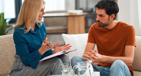 An addiction prevention and treatment specialist chats with a client in a comfortable office to support recovery.