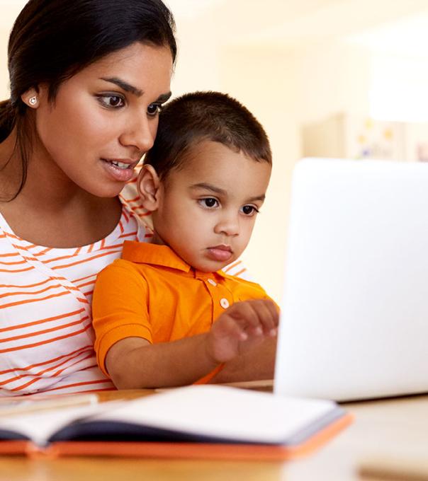 Mom sitting at a table with her son and a laptop