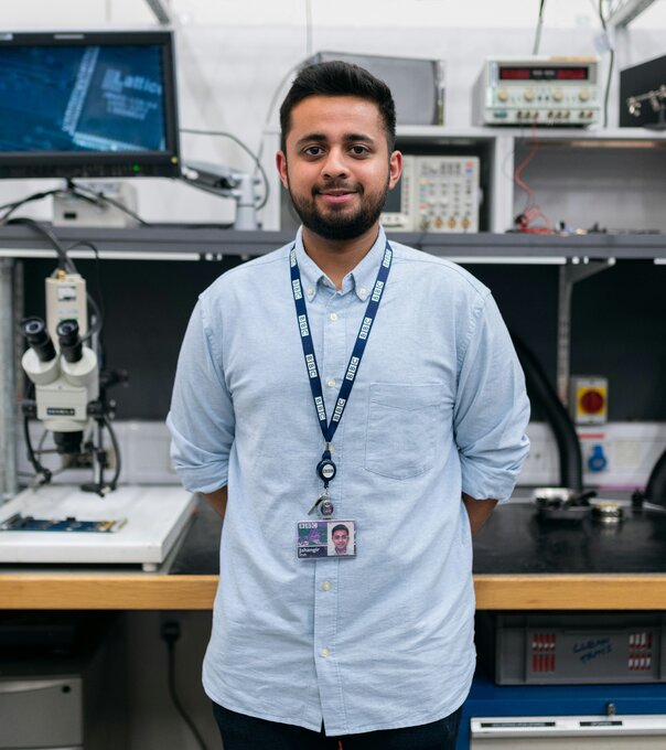 Engineering student standing in front of computers and lab equipment