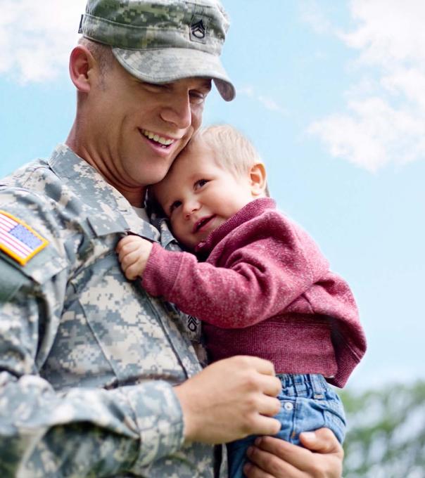 Military service member holds his child while in uniform