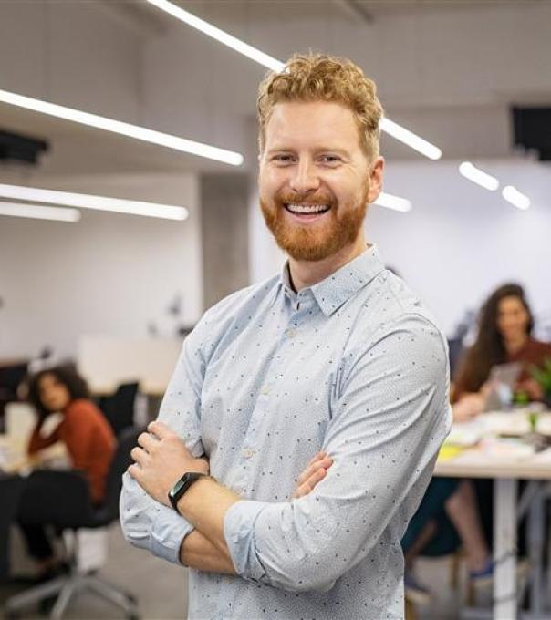 Man standing in a busy workshop and smiling 