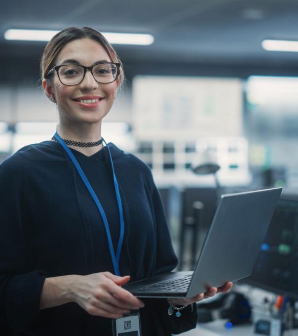 Woman stands holding a laptop in a workspace with servers