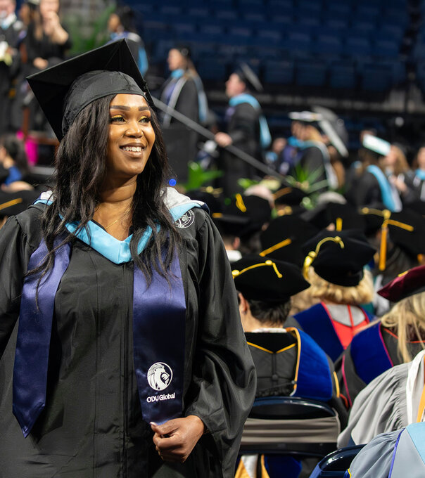 2024 Commencement image of a woman walking to the stage to receive her diploma with a smile