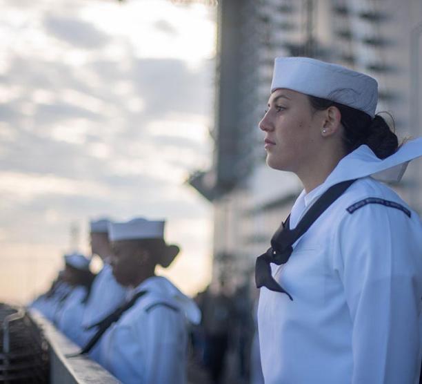 Sailor on the deck of a military ship pulling into port