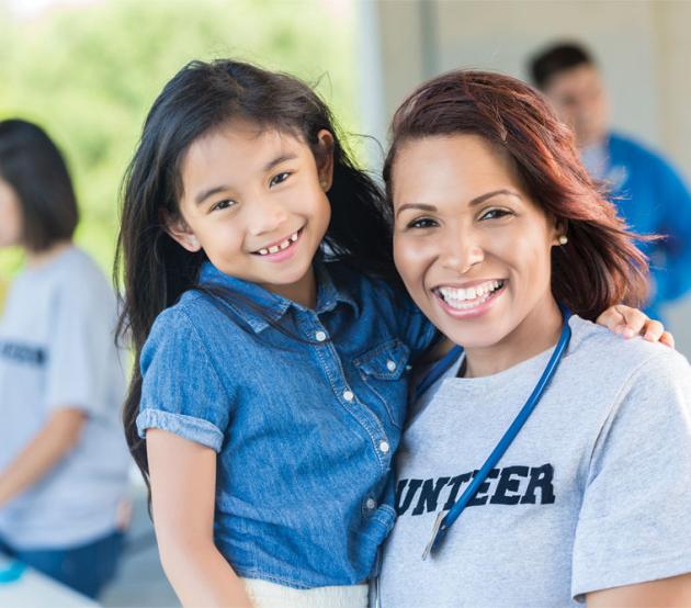 Female healthcare worker holding a young child after earning her public health bachelors degree online.