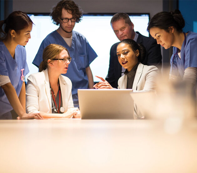 doctors, nurses, and healthcare administrators conferring around a computer