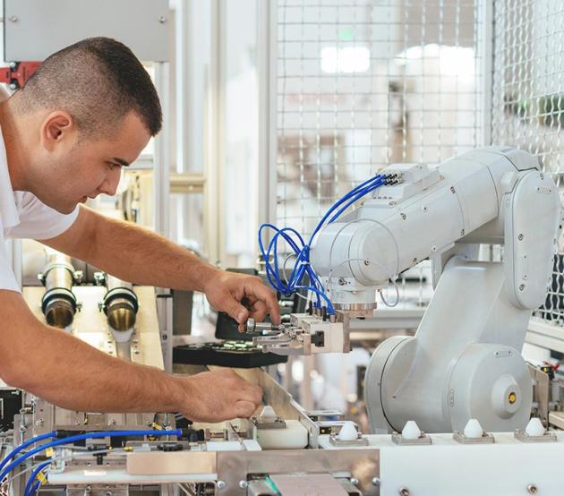 Engineer repairing a robotic arm in a manufacturing setting