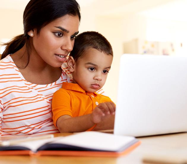 Mom sitting at a table with her son and a laptop