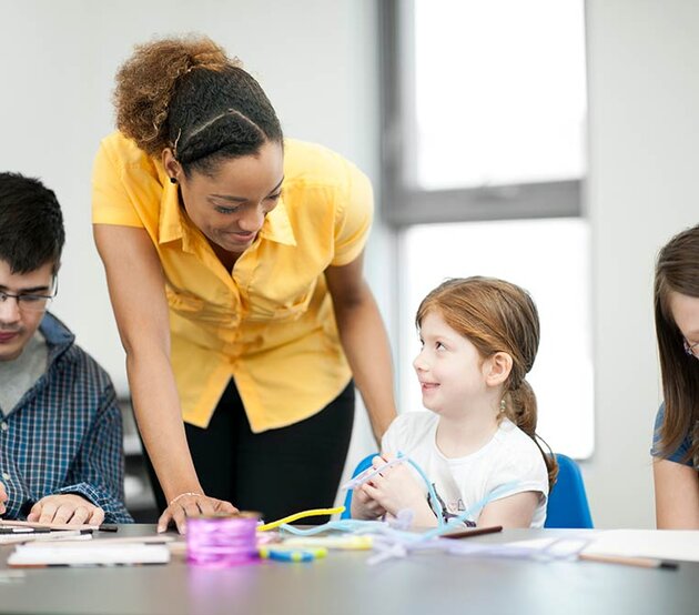 Special Education teacher helping students seated at a table with homework