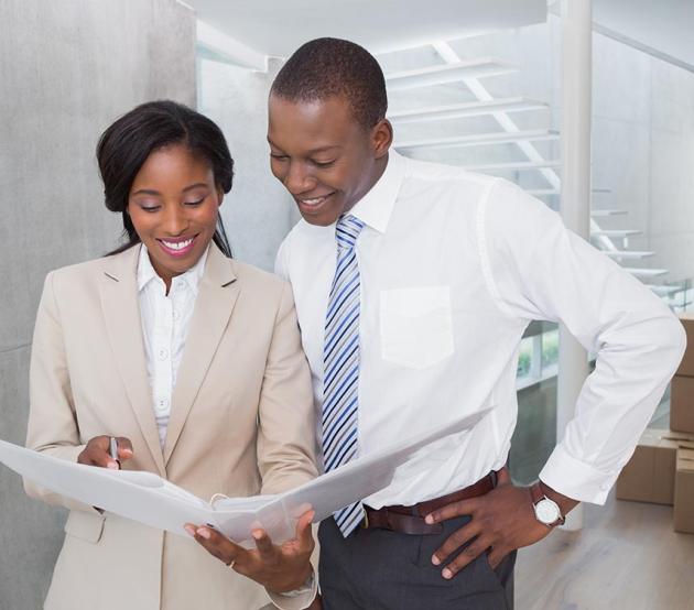 Two real estate developers in a new building look at a folder with information