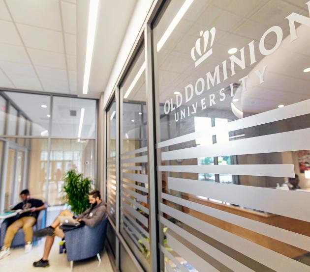 Old Dominion University logo on a glass window, with students seated and studying in the background.