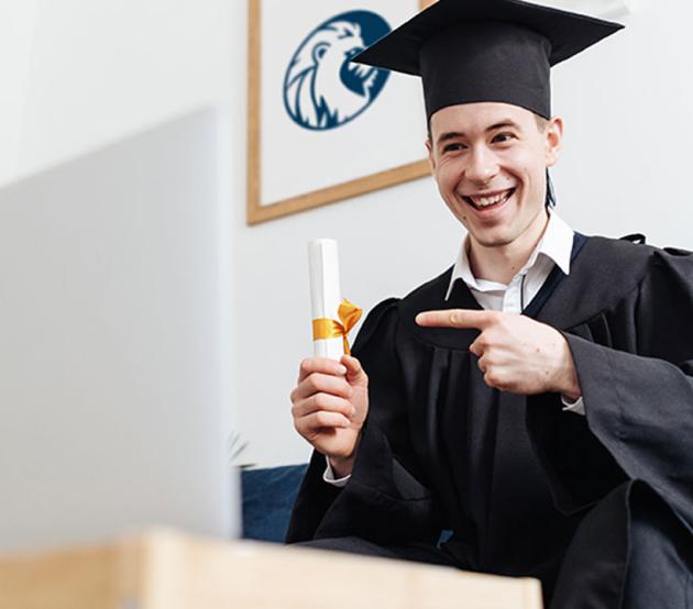 Male student holding a diploma for graduation on a blue couch