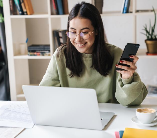 woman at computer with phone applying for college