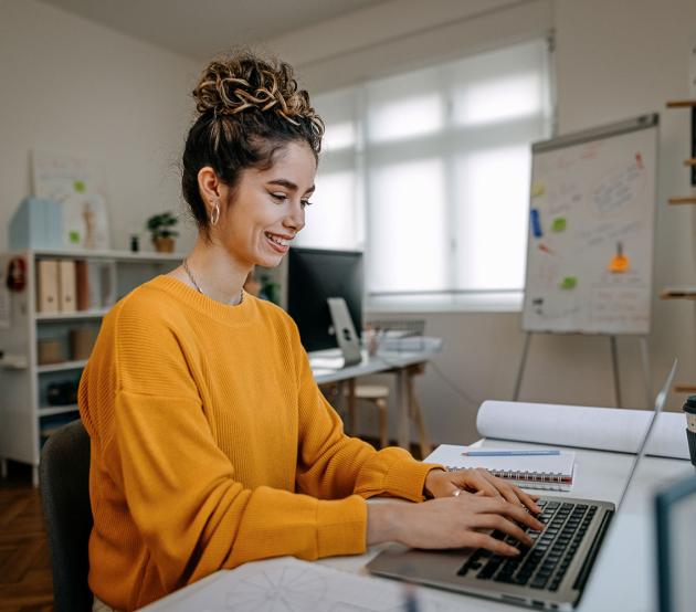 Woman sits at her computer searching for online degrees on ODUGlobal's website. Applying early can help ease your journey to online learning.
