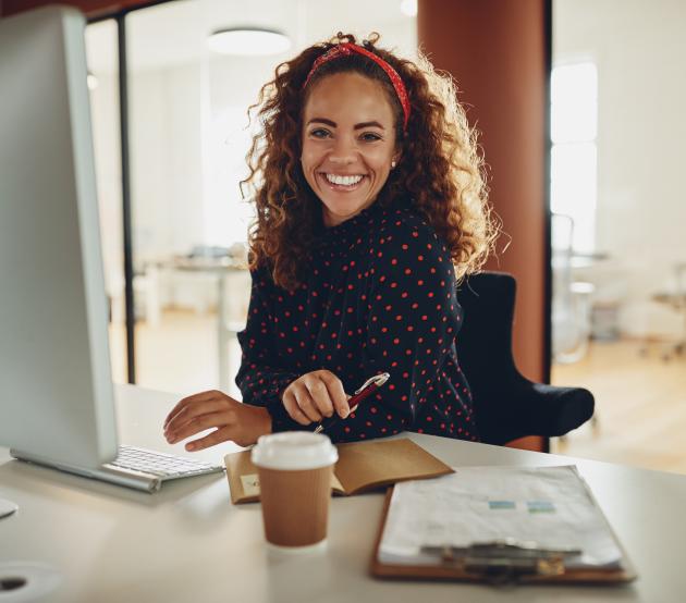 Woman working in accounting smiles at the camera while sitting at a computer. 