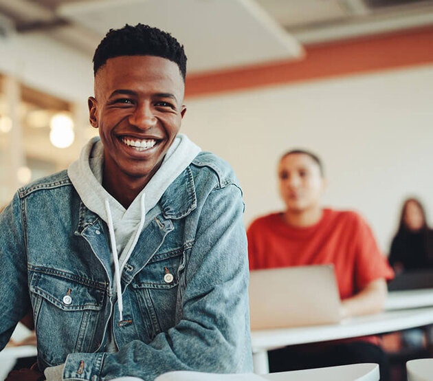 Smiling student seated at desk in classroom