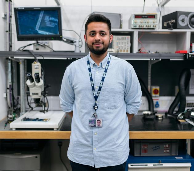 Engineering student standing in front of computers and lab equipment