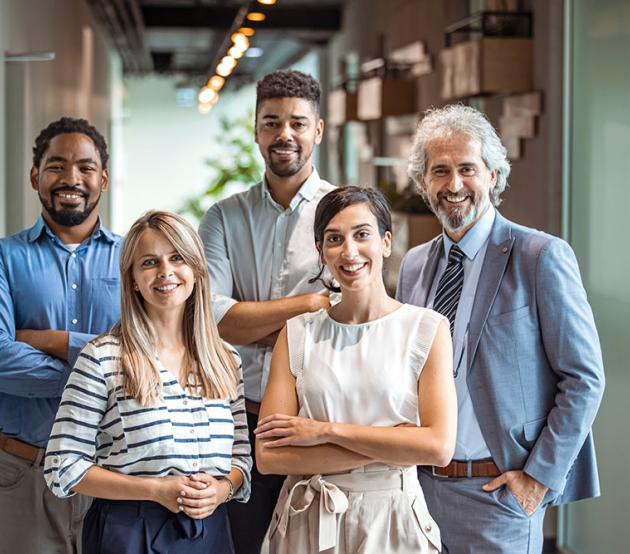 Coworkers pose and smile for a group photo in an office setting