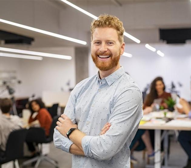 Man standing in a busy workshop and smiling 