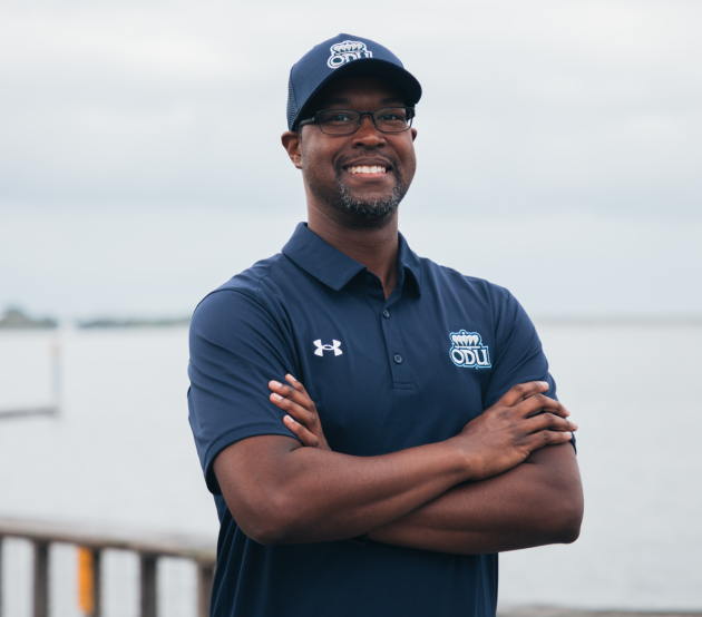 ODUGlobal student Will Chambers stands on the dock look at the camera and smiles proudly wearing ODU his gear.