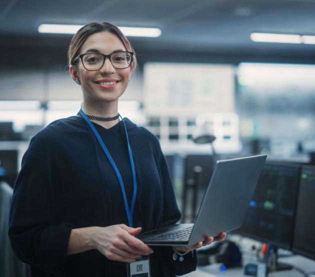 Woman stands holding a laptop in a workspace with servers
