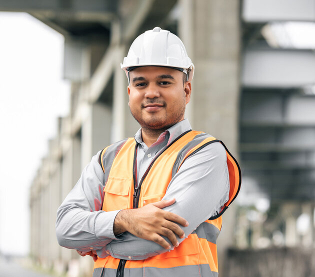 Construction worker stands at a construction site and smiles at the camera, ready to start his journey with ODUGlobal