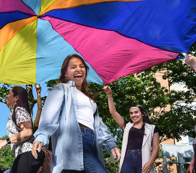 Woman smiling under a colorful parachute