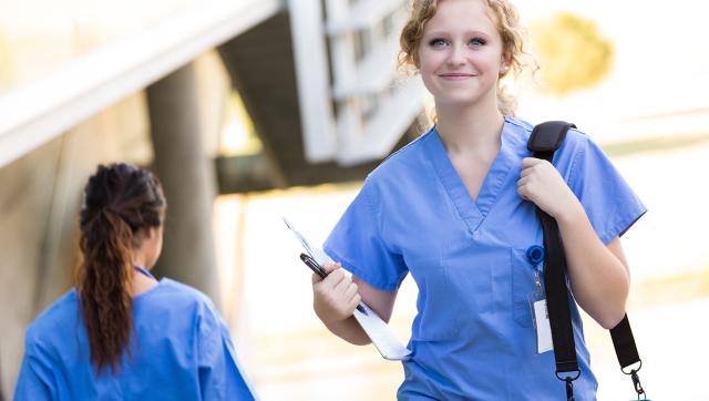 Nursing student with shoulder bag walking to class 