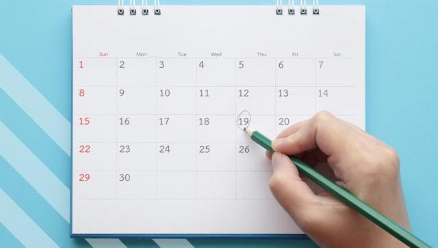 Calendar on blue background with hand recording a comment on a date