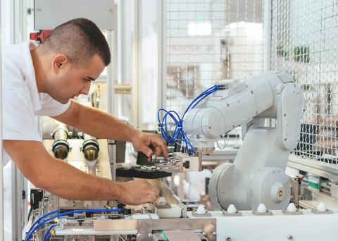 Engineer repairing a robotic arm in a manufacturing setting