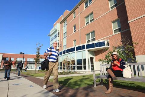 Students sit or walk outside a brick building on ODU's main campus