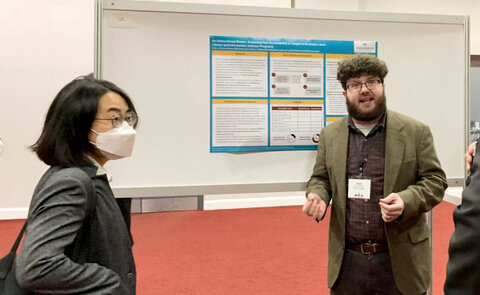 MLIS student Evan Dorman (right) talks about his research with visitors at a poster session.
