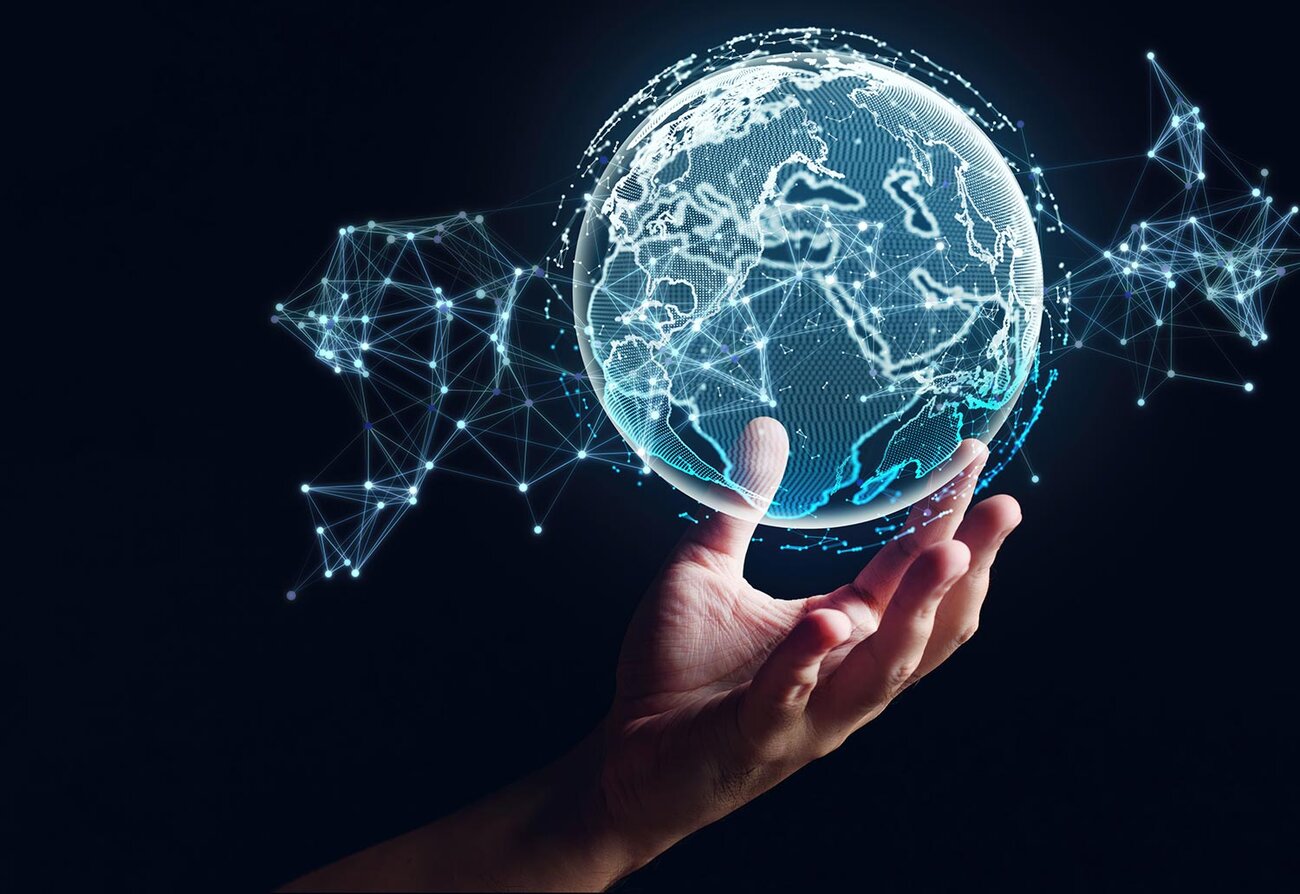 A human hand appears to hold up a hologram of the earth's globe.