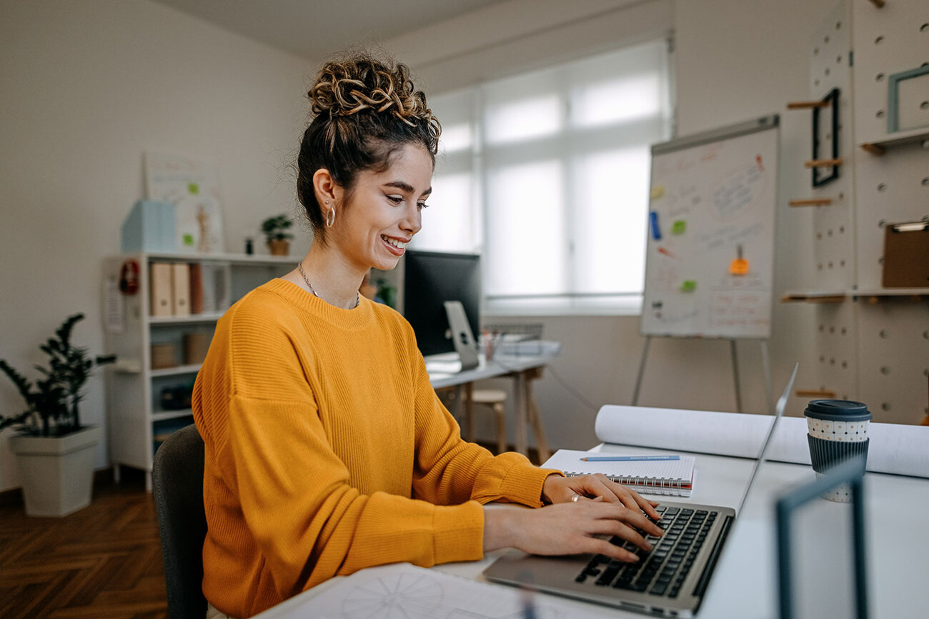 Woman sits at her computer searching for online degrees on ODUGlobal's website. Applying early can help ease your journey to online learning.