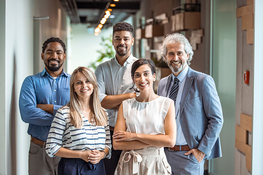 Coworkers pose and smile for a group photo in an office setting