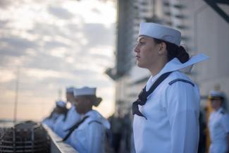 Sailor on the deck of a military ship pulling into port