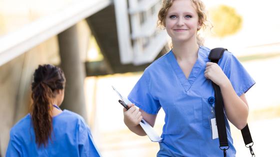 Nursing student with shoulder bag walking to class 