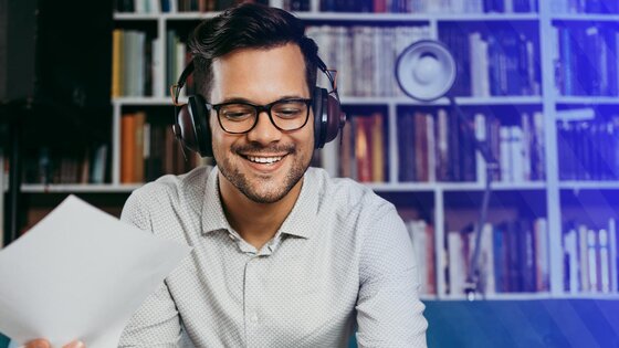 Smiling man with headphones looking at laptop