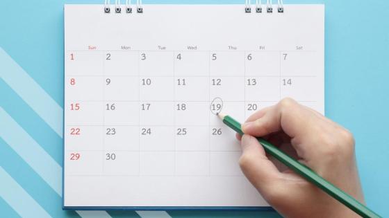 Calendar on blue background with hand recording a comment on a date