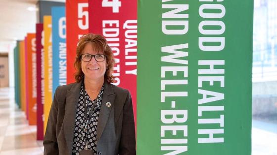 Janice Hawkins stands in front of colorful banners promoting good health at a special event.