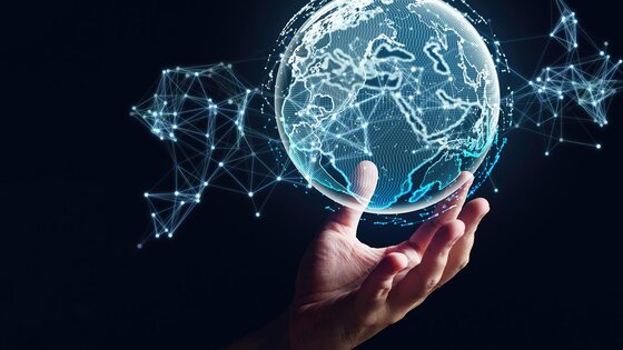 A human hand appears to hold up a hologram of the earth's globe.