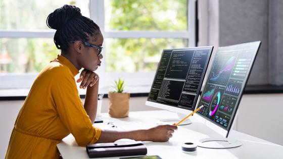 A data science professional works with code and data visualization on a desktop computer.